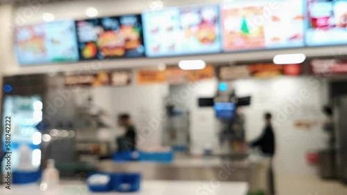 In blur, a trade workers at a fast food making a food at kitchen behind the cash register. Restaurant business at a food court in a shopping center. Unrecognizable place of sale of food.