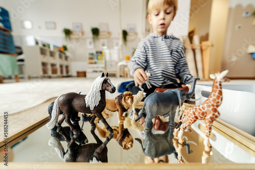 Selective focus on animals toys with a little boy playing with it in montessori kindergarten.