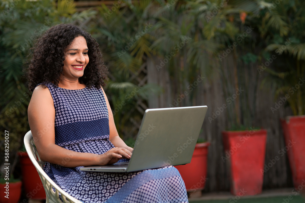 Indian woman sitting outdoor and using laptop. Indian woman sitting outdoor and using laptop.