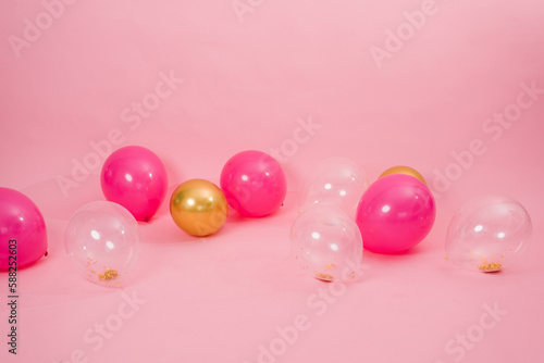 Beautiful multicolored pink, gold and transparent with confetti or sequins lie on a pink background in a chaotic order. Concept of Valentine's day, birthday, mother's day