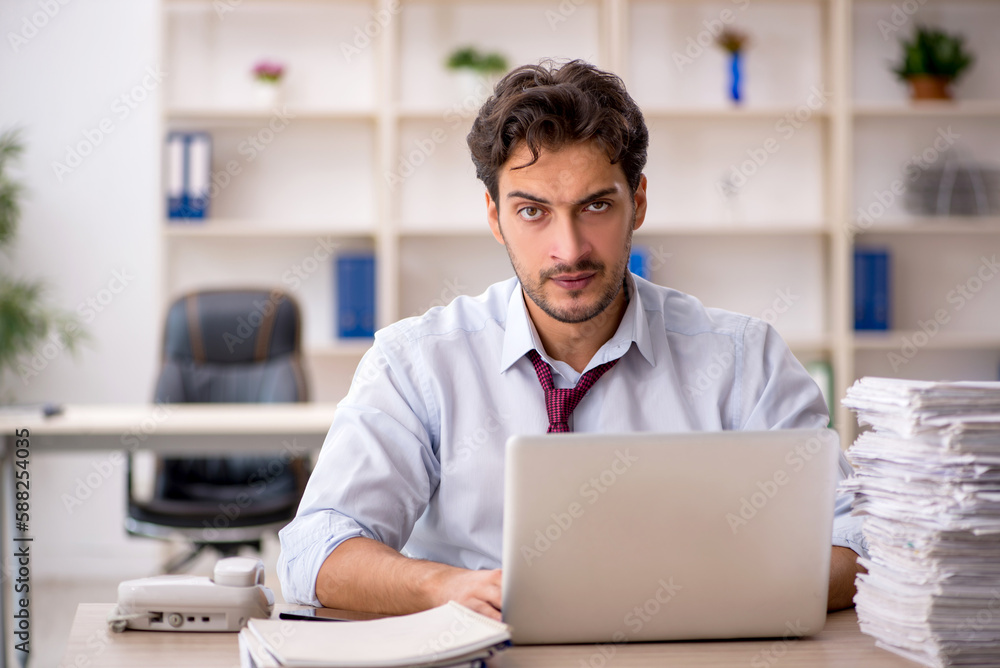Young male employee and too much work in the office Young male employee and too much work in the office
