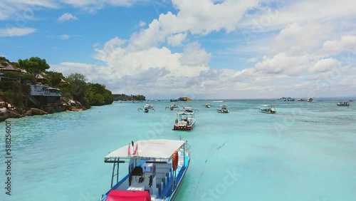 Picturesque aerial view: Traditional indonesian Jukung boats in clear turquoise blue water in in Nusa Lembongan, Jungut Batu Beach, Selat Ceningan, Bali. Houses and with palm trees near nearby. Drone photo