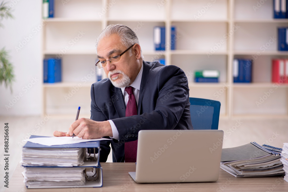 Old male employee sitting at workplace Old male employee sitting at workplace