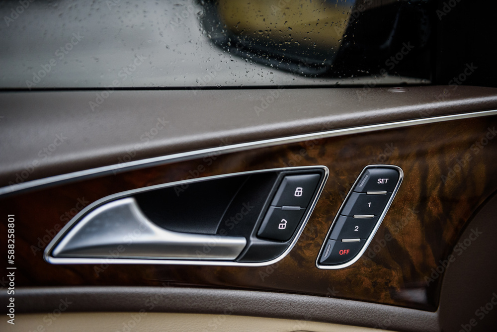 Obraz premium Car inside door chrome handle. Panel with seat settings driver's. Buttons to adjust driver's seat memory. Closeup car interior. Car door control left panel. Blocking opening and closing of doors.