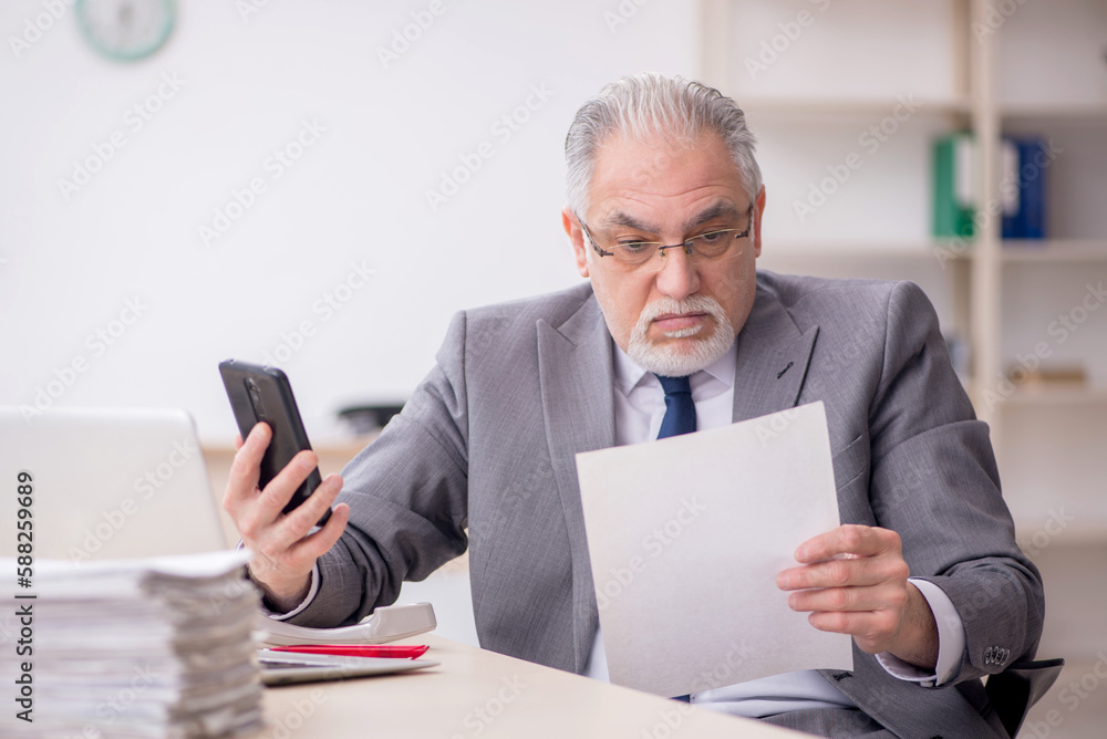 Old male employee working in the office Old male employee working in the office