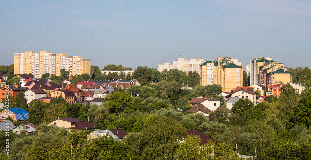 Obraz premium Panoramic top view of the modern houses of the residential area of the city of Vladimir in Russia and a park with lush green foliage of trees on a sunny summer day