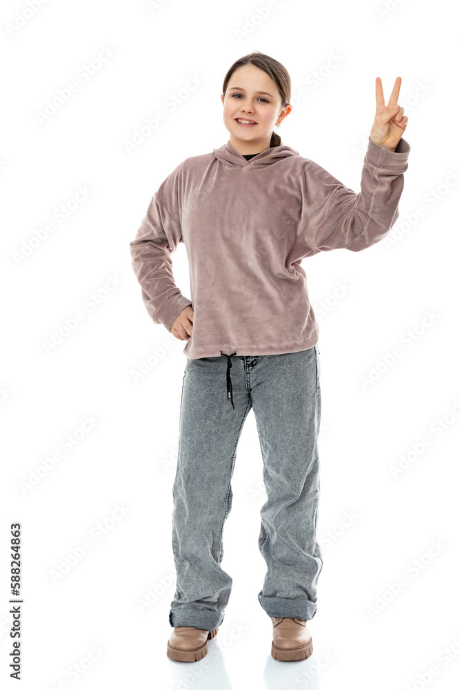 Full-length portrait of happy child shows v-sign symbol of peace with fingers isolated on white background. Twelve year old girl doing victory sign and smiling to the camera in studio. Full-length portrait of happy child shows v-sign symbol of peace with fingers isolated on white background. Twelve year old girl doing victory sign and smiling to the camera in studio.