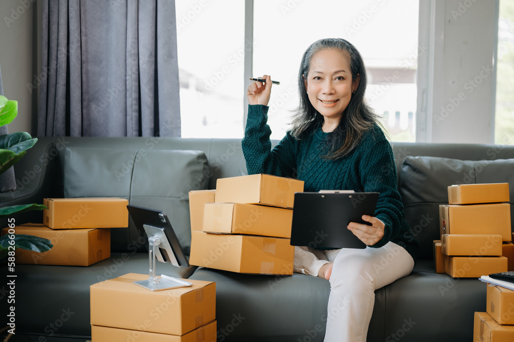 Startup small business SME, Senior woman hand using smartphone or tablet taking receive and checking online purchase shopping order to preparing pack product box. business online shopping concept Startup small business SME, Senior woman hand using smartphone or tablet taking receive and checking online purchase shopping order to preparing pack product box. business online shopping concept
