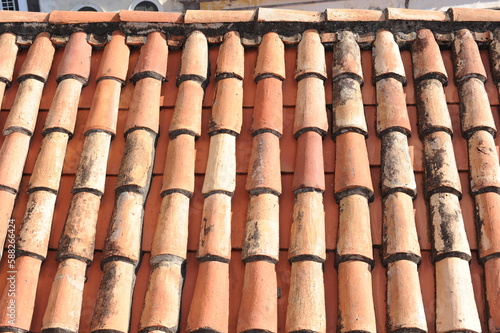 Red and orange roof tiles texture pattern on roof of an old historical building