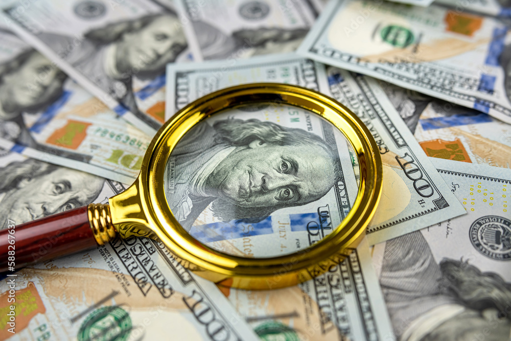 Magnifying glass on us dollar bills as background Magnifying glass on us dollar bills as background