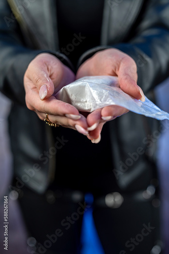 closeup of drug dealer wear black cloth hold packet of heroin or cocaine