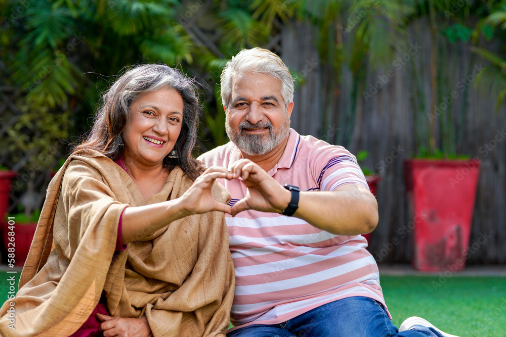 Indian senior couple smiling and making heart shape with hand. Stock ...