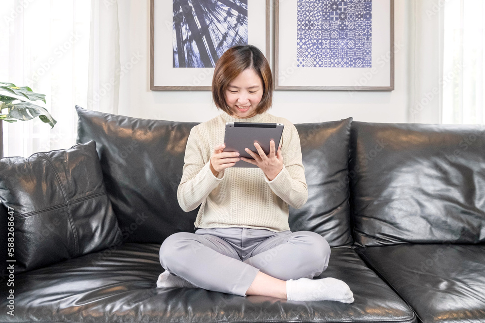 Happy relaxed young woman sitting on the sofa using a mobile phone ...