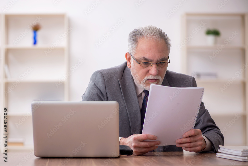 Old male employee working in the office Old male employee working in the office