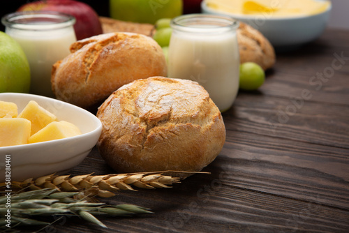 Jewish Shavuot Holiday Card. Dairy Products, Fruits, Cheese, Bread, Milk on Brown Wooden Background. photo