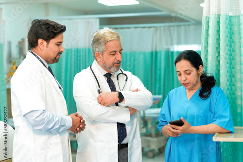 Senior doctor watching some detail in smartphone and discuss to other staff
