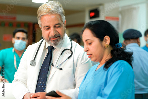 Senior doctor watching some detail in smartphone and discuss to other staff