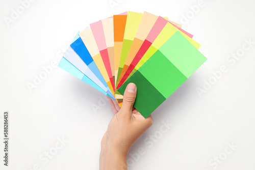 Female hand holding color palettes on white background © Atlas