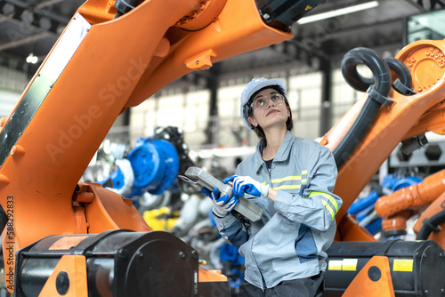 Female industrial engineer maintenance mechanic orange robot frame then assembly to robotic automation machine. Industry 4.0 is robotization technology or smart digital automation in modern factory.