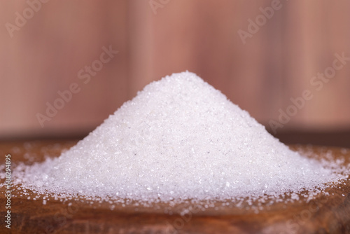 Granulated sugar. White refined sugar on wood background. Close up