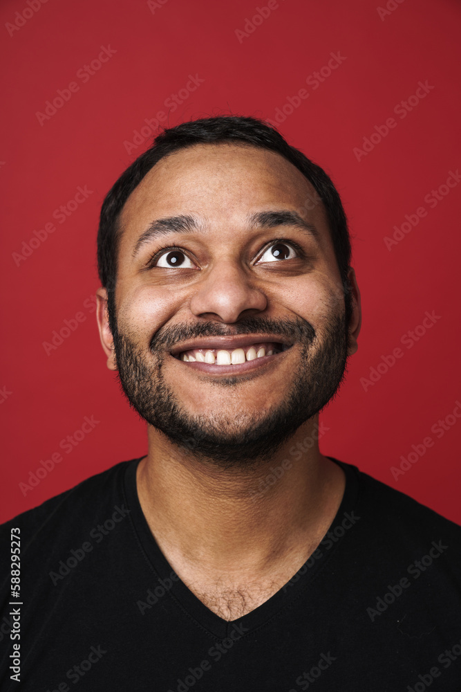 Indian man looking upward and smiling isolated over red background Indian man looking upward and smiling isolated over red background