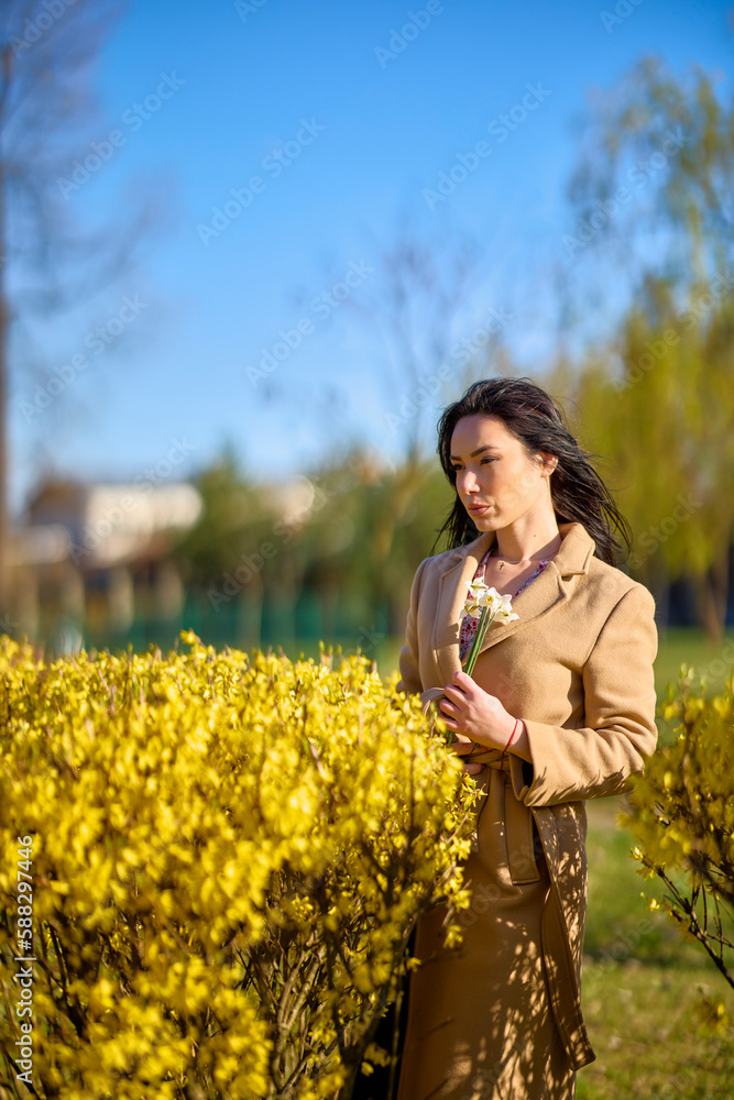 beautiful woman posing by a blooming yellow tree on a sunny spring day. beautiful woman posing by a blooming yellow tree on a sunny spring day.
