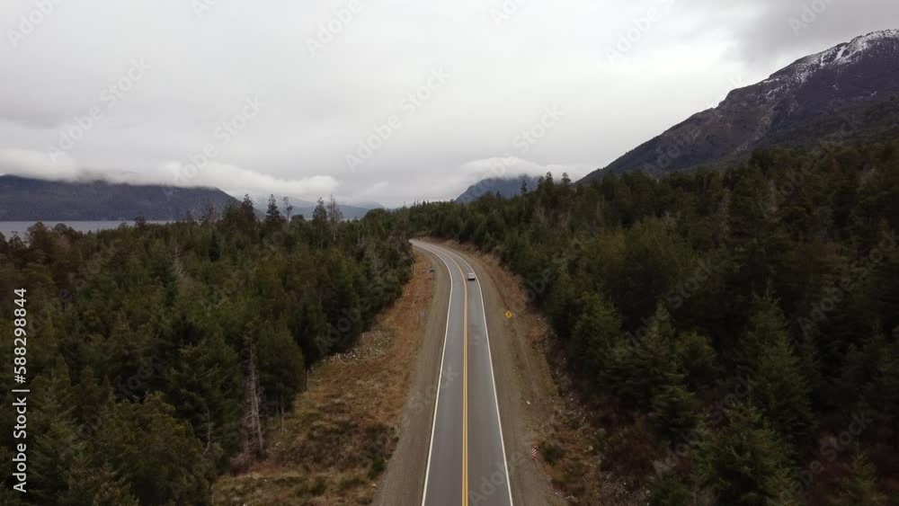 Car driving on a road in the middle of a forest in Patagonia with mountains in the background Car driving on a road in the middle of a forest in Patagonia with mountains in the background