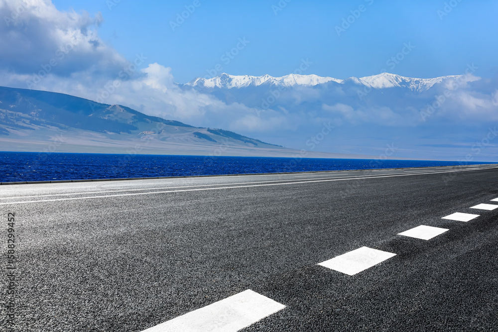 Asphalt road and blue lake with mountain background