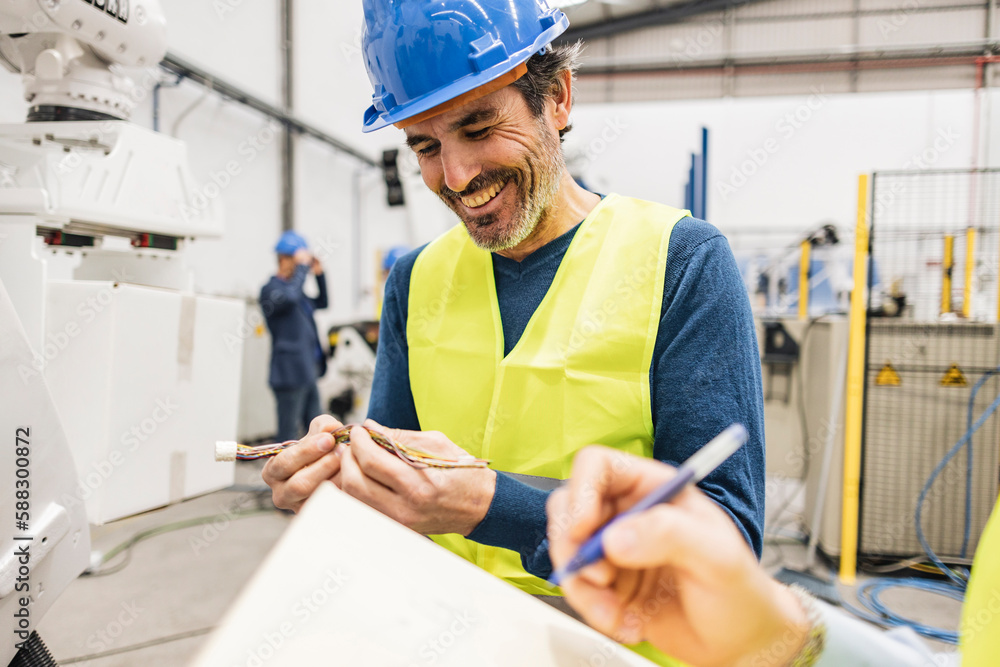 Happy engineer examining machine wire in industry Happy engineer examining machine wire in industry