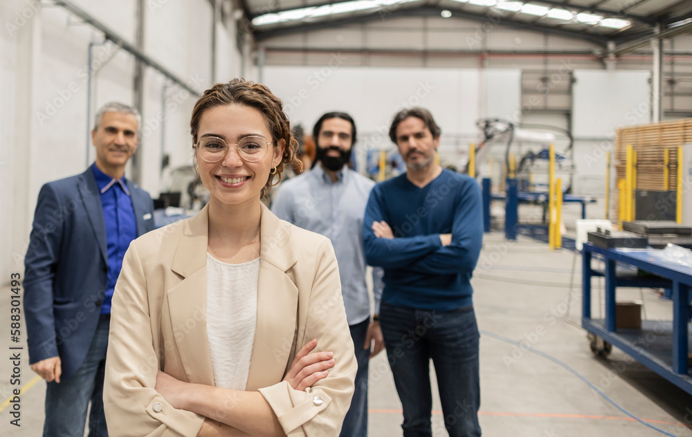 Happy engineer standing with arms crossed in front of colleagues