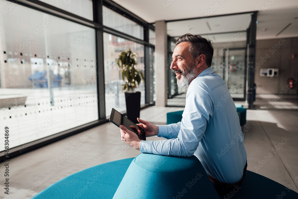 Happy businessman sitting with tablet PC in office Happy businessman sitting with tablet PC in office