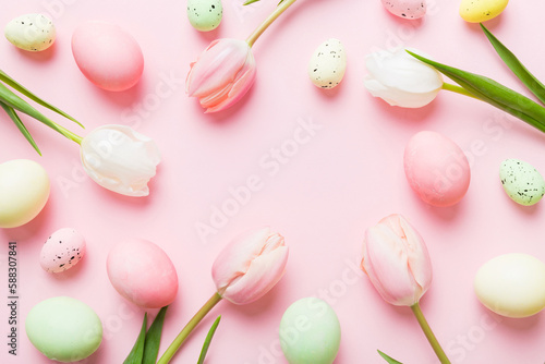 Happy Easter composition. Easter eggs on colored table with yellow Tulips. Natural dyed colorful eggs background top view with copy space