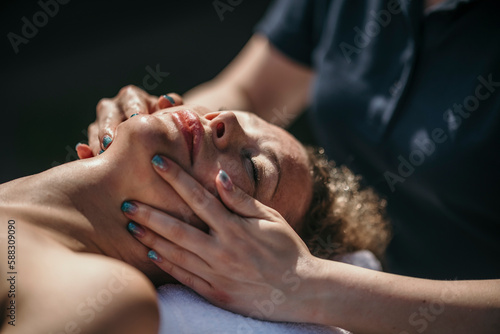 Massage therapist doing facial massage of customer at spa photo