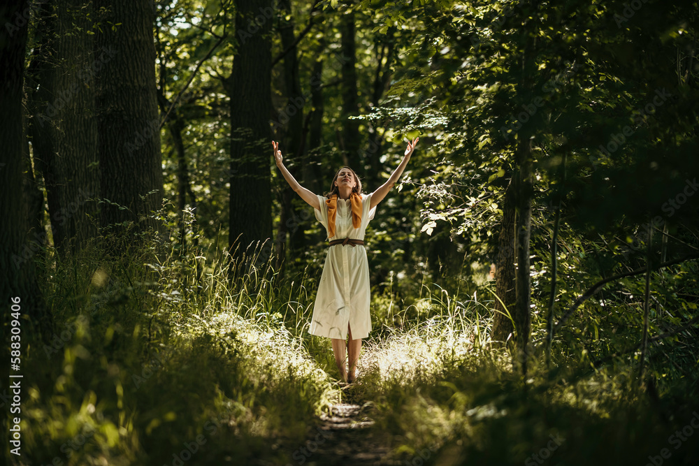 Woman with arms raised standing in forest Woman with arms raised standing in forest