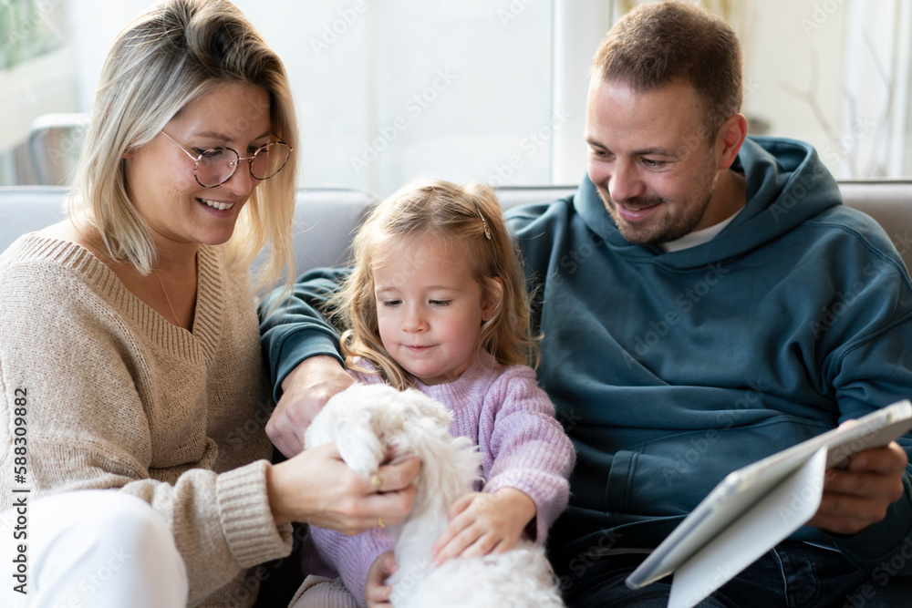 Daughter petting dog sitting by parents at home Daughter petting dog sitting by parents at home