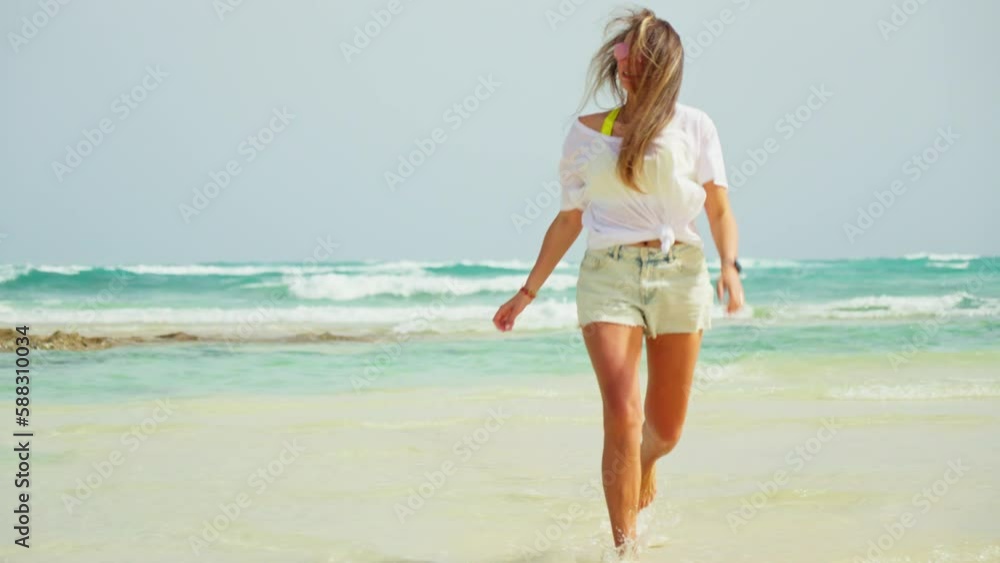 The girl runs along the beach, approaches. White sand and blue sea. The girl runs along the beach, approaches. White sand and blue sea.