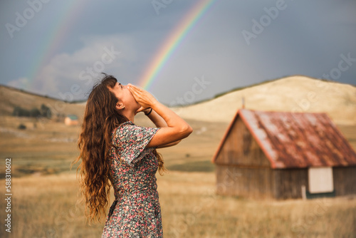 Optical illusion of rainbow coming out from mouth of woman standing in field