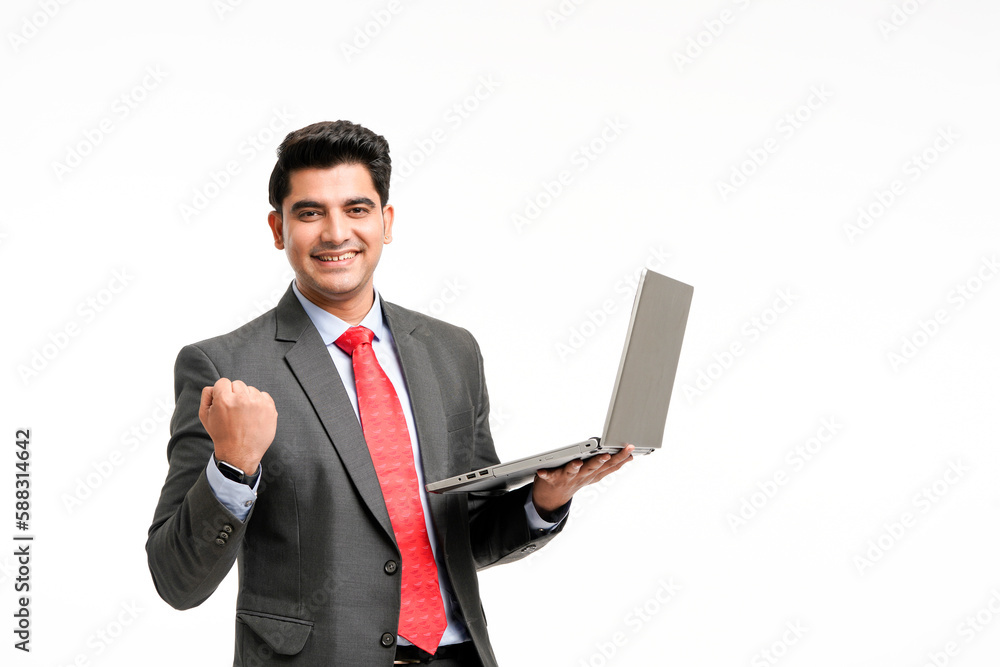 Young indian businessman in suit, holding laptop and giving a winning expression. Young indian businessman in suit, holding laptop and giving a winning expression.
