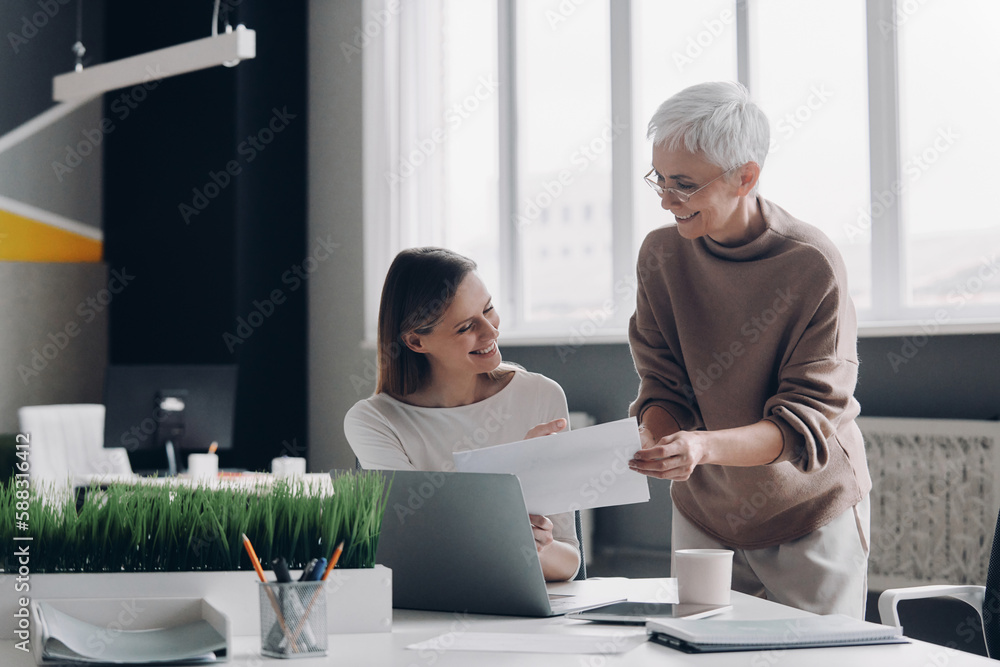 Two happy businesswomen analyzing data while working in the office together Two happy businesswomen analyzing data while working in the office together