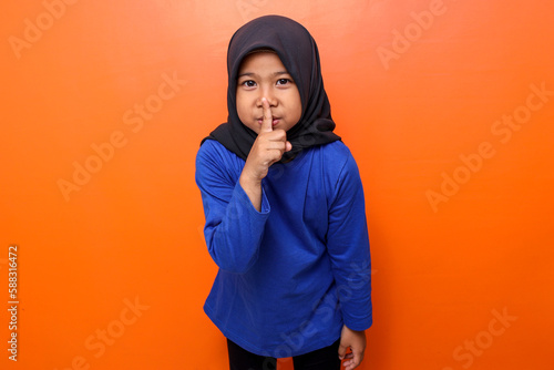 Muslim kid gesturing to maintain silence photo