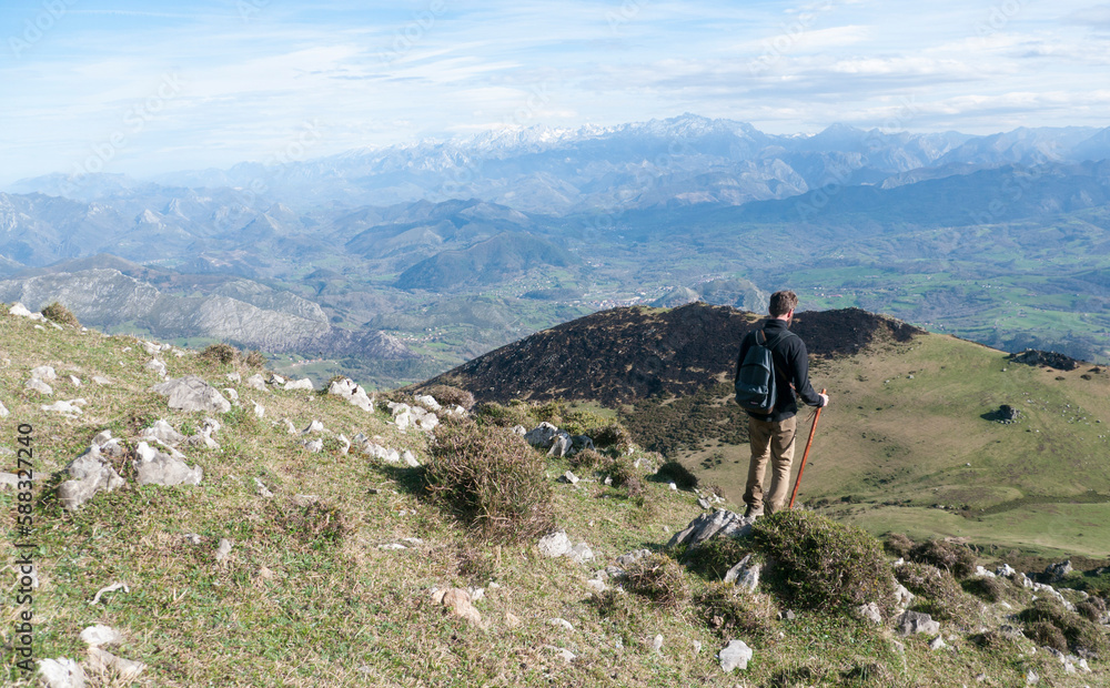 Hombre joven barbudo descendiendo por ladera de montaña de Asturias