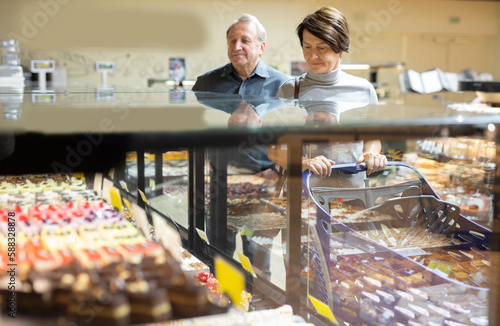 woman chooses cakes at showcase of confectionery department