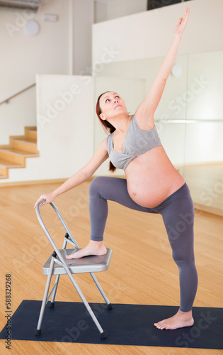 Pregnant woman is engaged in yoga. Chair Low Lunge Twist Pose or Parivrtta Sanchalasana photo