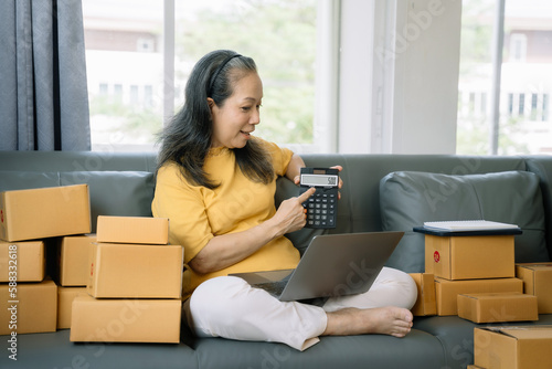 adult woman working at home about online business. Business owner women using calculator and smart phone working at home.