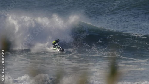 A jet ski rider rides a wave and then gets catapulted into the air to perform a spin trick photo