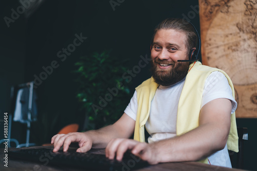 Cheerful man in headphones playing computer game