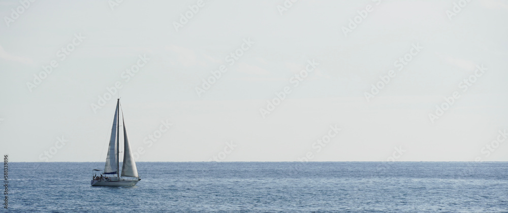 Sailboat in the water with space for text. White sailing boat. Boat sailing on summer vacation in the Mediterranean Sea. Sailing boat racing with white sails in open sea.
