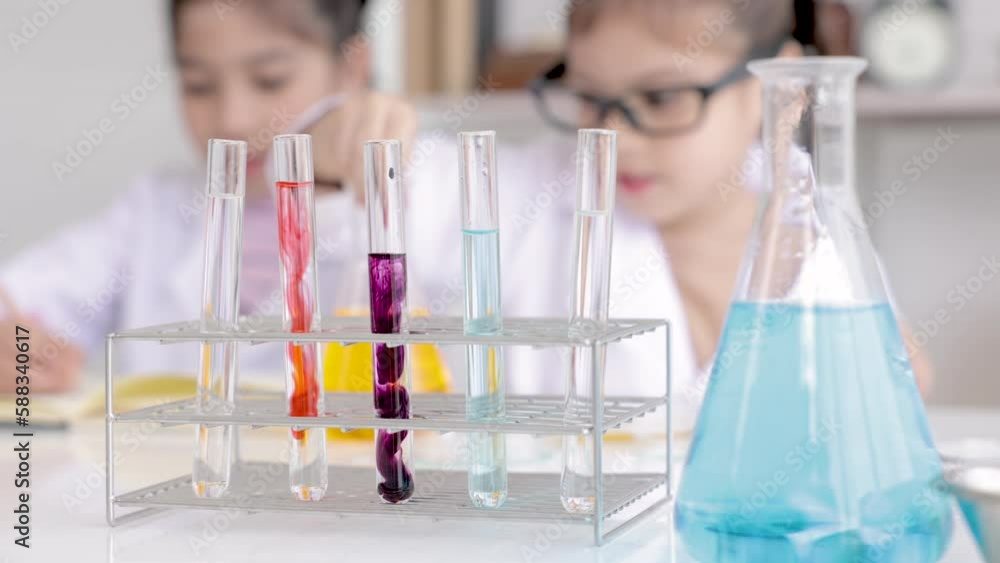 Elementary student wearing lab coat learning chemistry in school ...