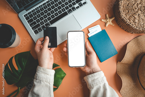 Woman holding credit card and smartphone buying plane tickets online, top view