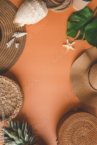 Colorful summer female fashion outfit flat lay. Straw hat, bamboo bag, wicker shoes, pineapple over beige background, top view, wide composition. Summer fashion, holiday concept